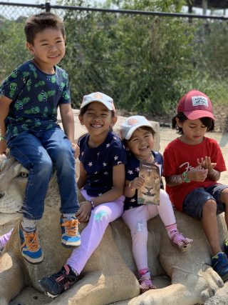 Kids smiling and laughing on a model of a lioness